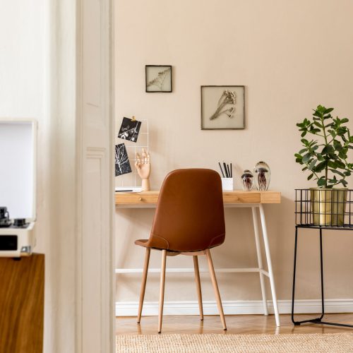 Design scandinavian interior of home office space with a lot of mock up photo frames, wooden desk, brown chair, plants, office and personal accessories. Stylish neutral home staging. Template.